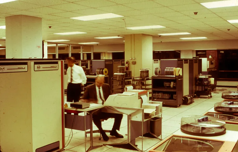Engineers working in a vintage computer room with tape drives