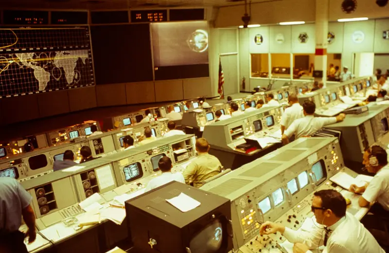 Engineers at their consoles in a 1960s mission control room